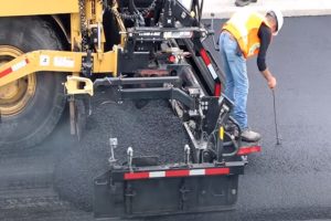 Paving worker inspecting newly constructed asphalt pavement