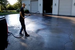 Paving worker spraying sealcoat on the driveway